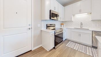 A kitchen with white cabinets and a white door.