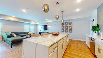 A modern kitchen with a white island and wooden floors.