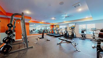 A gym with a variety of equipment including weights and cardio machines.