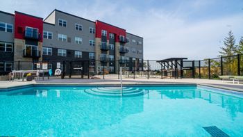 A swimming pool in front of a multi-story apartment building.
