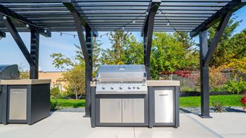 A modern outdoor kitchen setup with a grill, sink, and cabinet.