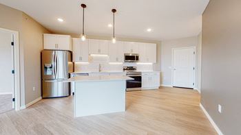 A kitchen with a white island and wooden floors.