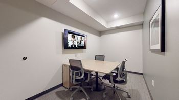 A conference room with a table, chairs and a screen on the wall.