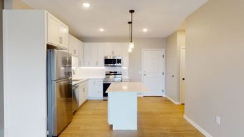A modern kitchen with stainless steel appliances and wooden floors.