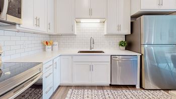 A kitchen with white cabinets and a stainless steel refrigerator.