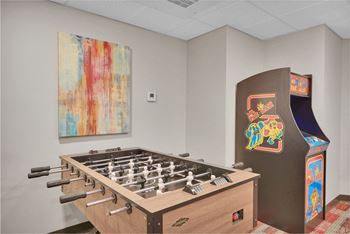 A foosball table sits next to a vintage arcade machine.