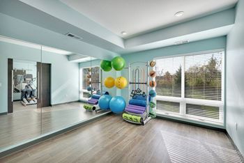 A room with a mirror, exercise equipment, and a window with blinds.