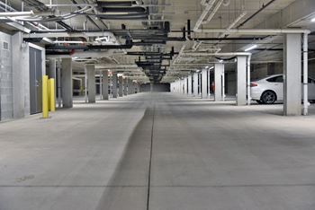 A long, empty parking garage with a white car parked on the right side.