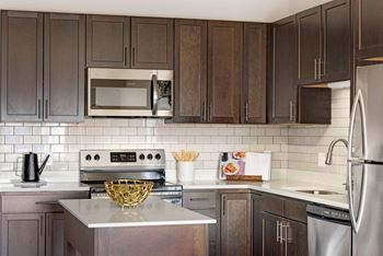 A kitchen with dark brown cabinets and a stainless steel refrigerator.