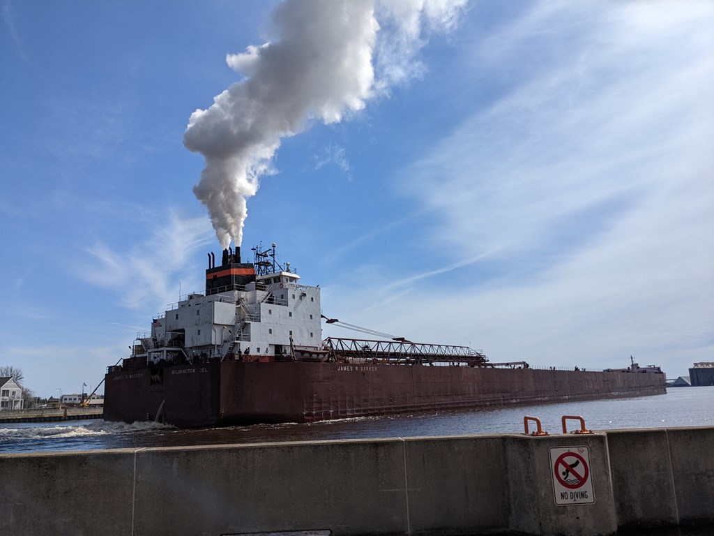 a large ship in the water with smoke coming out of it