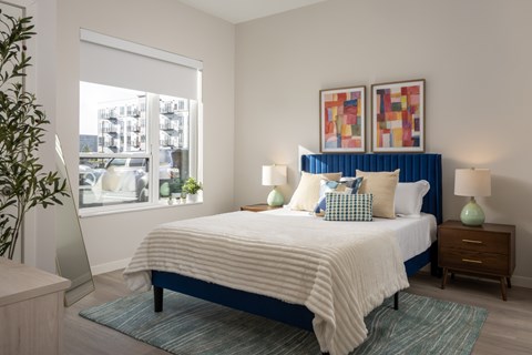 A bedroom with a large bed and a window overlooking a cityscape.