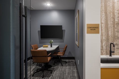 A conference room with a table, chairs, and a sign on the wall.