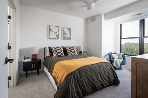 A bedroom with a bed, a nightstand, and a ceiling fan.