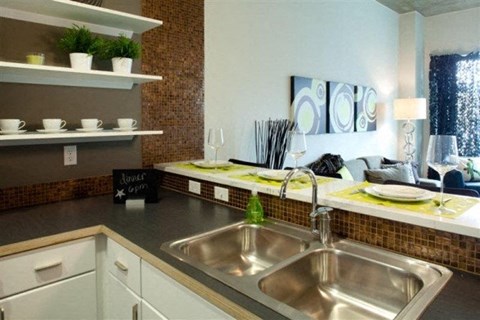 A kitchen with a sink and a counter with a sign that says "House Opens".