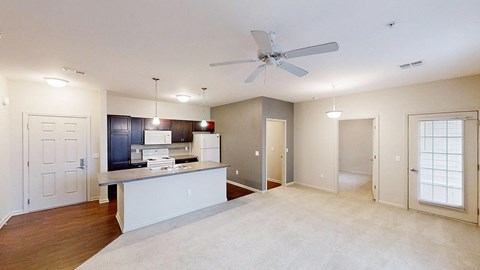 an empty living room with a kitchen and a ceiling fan