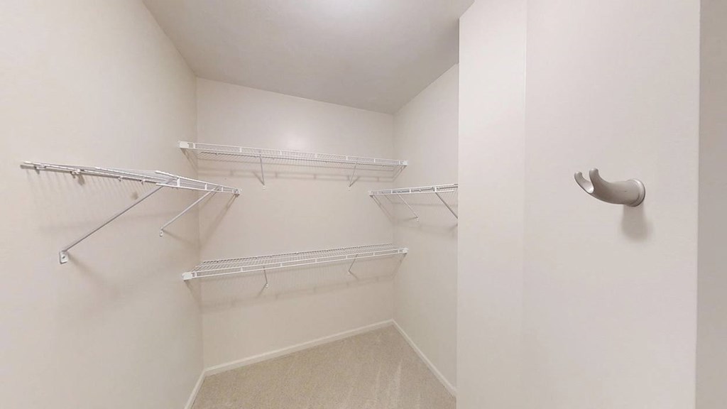 a spacious walk in closet with white walls and shelves