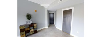 a hallway with a grey door and a vase on a dresser