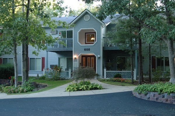 the front of a gray house with a sidewalk and trees