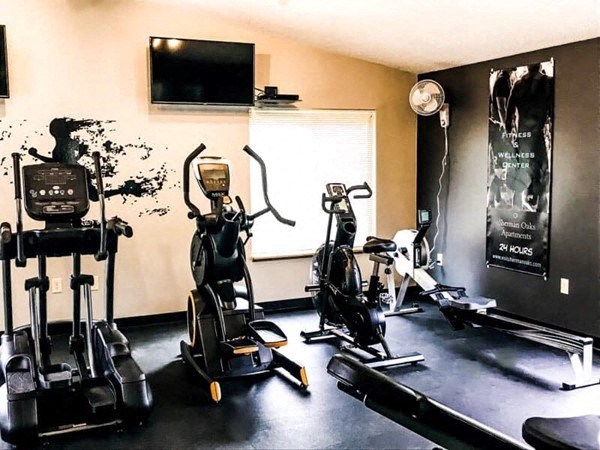 a gym with several exercise machines and a tv