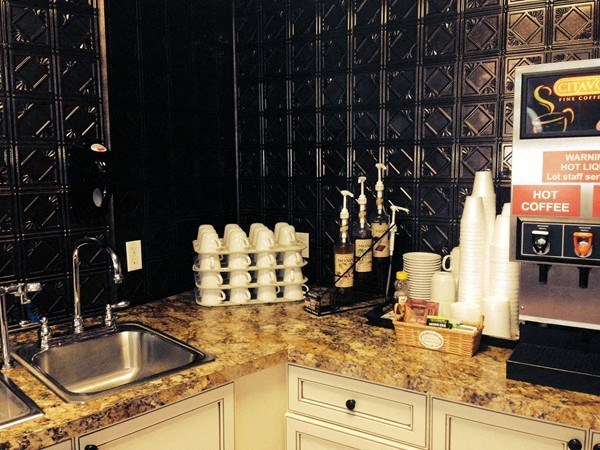 a kitchen counter with a sink and some coffee cups on it
