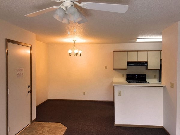 an empty room with a kitchen and a ceiling fan