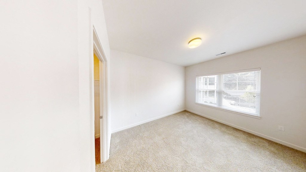an empty bedroom with a large window and a door to a closet