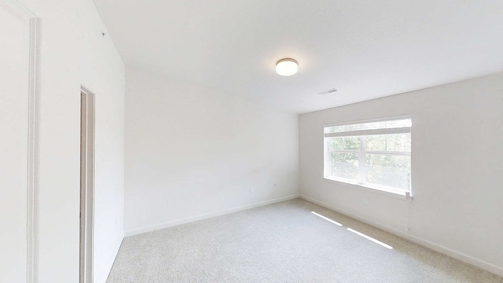 an empty room with a window and white walls