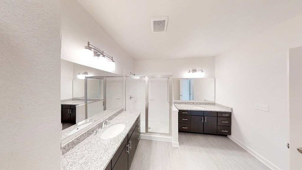 a bathroom with a shower and sinks and a mirror