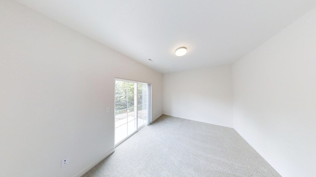 a living room with white walls and a sliding glass door