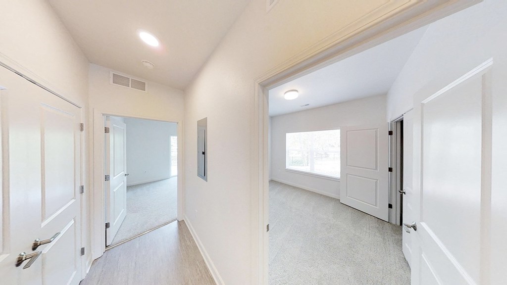 an empty bedroom and hallway with white doors and white walls