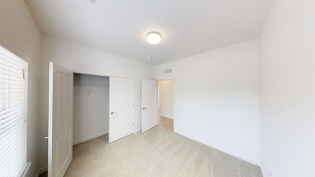 an empty room with white walls and white closet doors