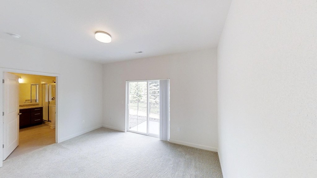 an empty living room with white walls and a sliding glass door