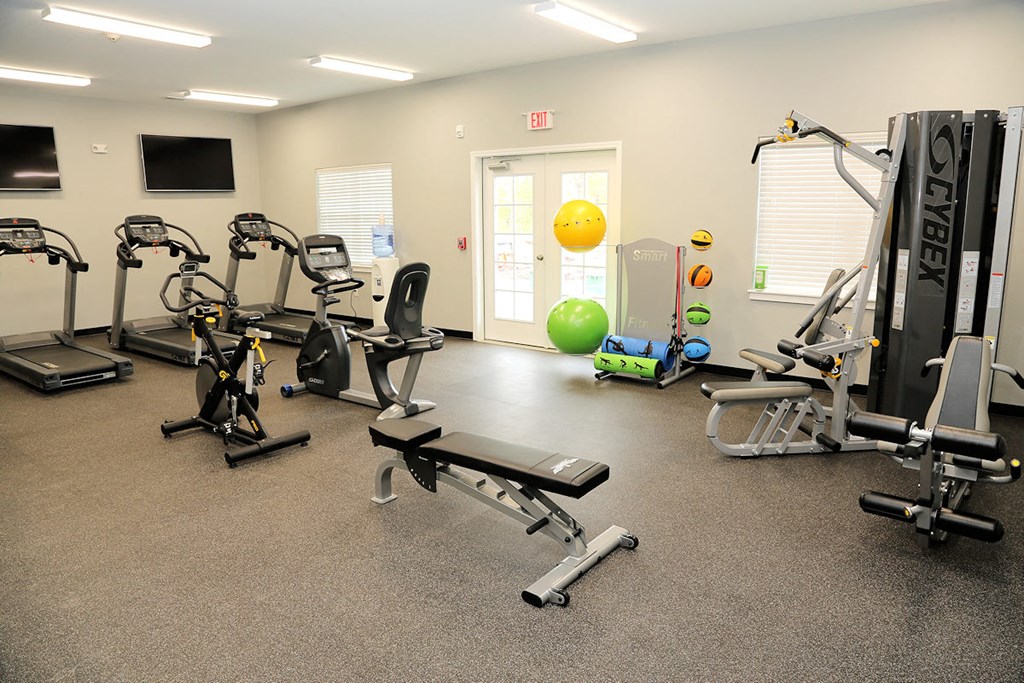 a gym with exercise equipment and a yellow ball in the corner