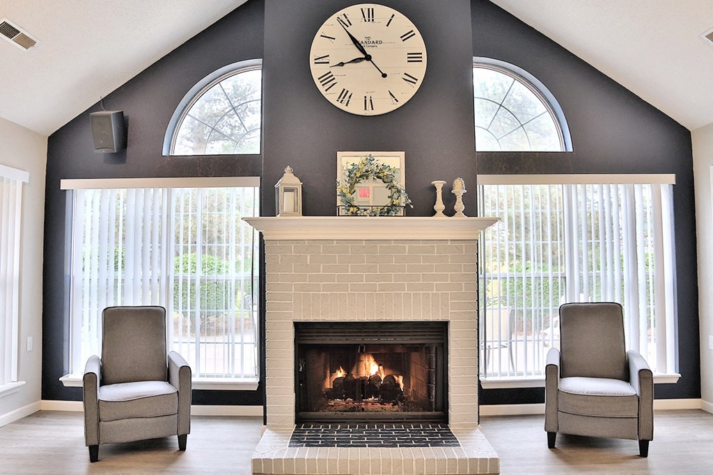 Clubhouse with two chairs and a fireplace with a large clock on the wall