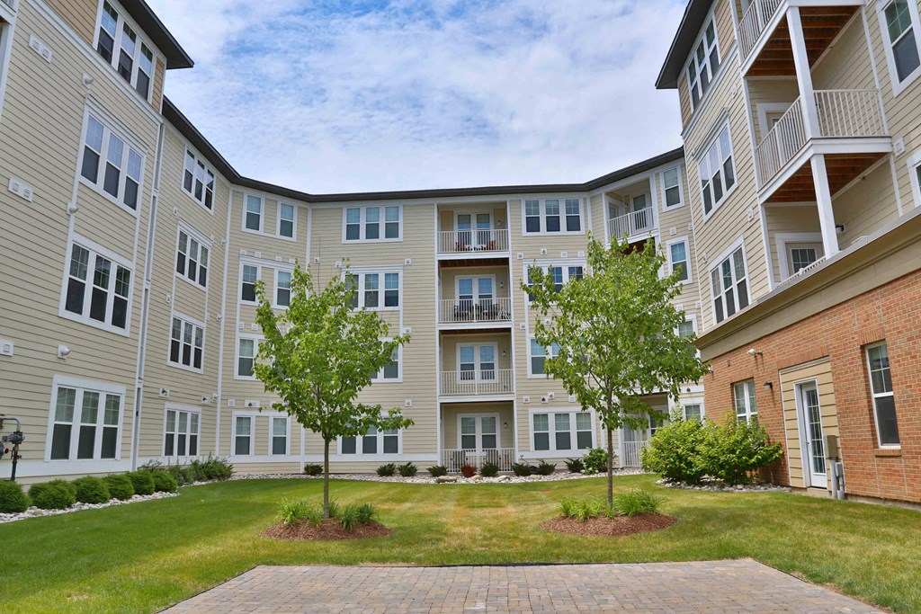 an exterior view of an apartment building with grass and trees