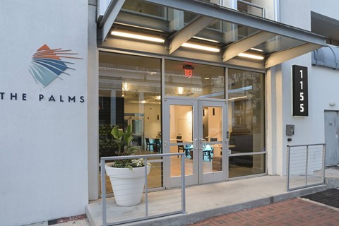 The Palms building has a glass entrance with a potted plant in front.
