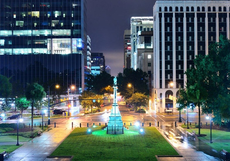 a city at night with a statue in the middle of a park