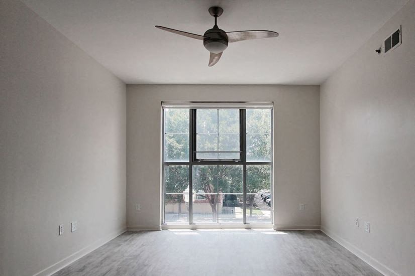 an empty living room with a ceiling fan and a window