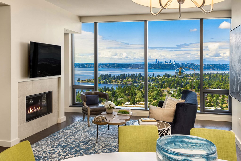 a living room with a fireplace and a view of a city and a lake at Two Lincoln Tower, Bellevue