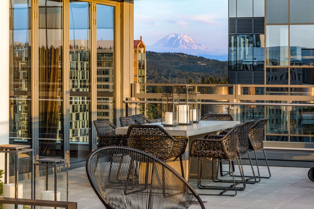 a table and chairs on a balcony with a view of a mountain at Two Lincoln Tower, Bellevue, WA, 98004