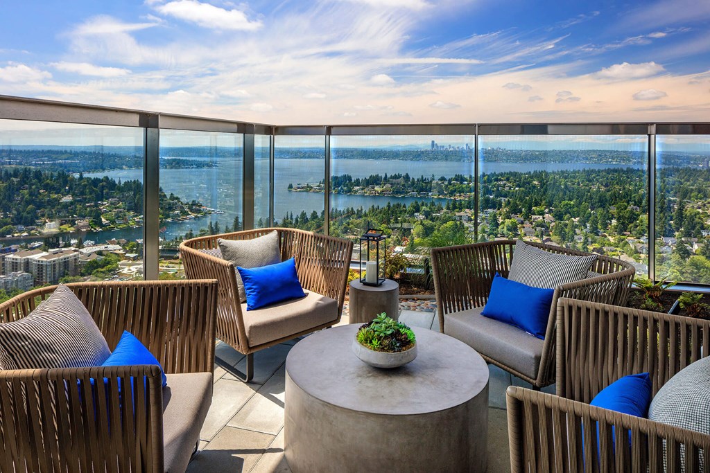 a balcony with chairs and a table and a view of a city and the water at Two Lincoln Tower, Bellevue, WA, 98004