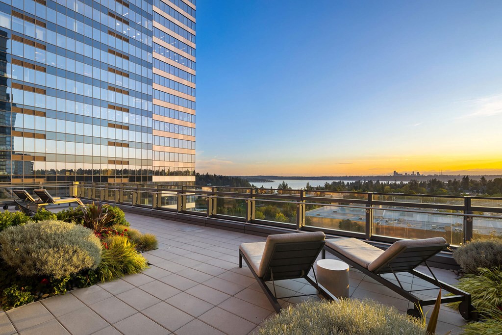 a terrace with chairs and a table overlooking the water and a tall building at Two Lincoln Tower, Bellevue, WA, 98004