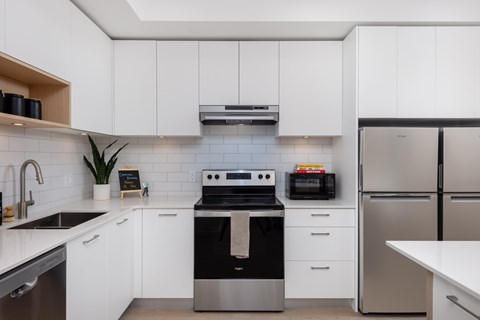 A modern kitchen with white cabinets and stainless steel appliances.