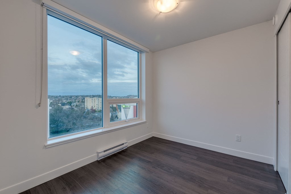 a bedroom with a large window and hardwood floors