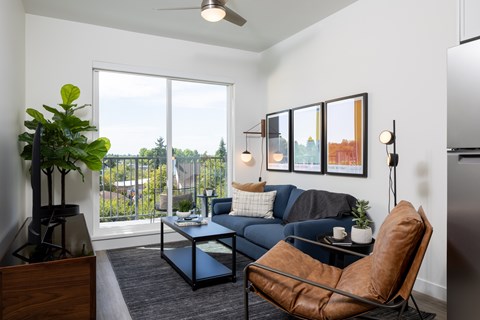 A living room with a couch, chair, and a potted plant.