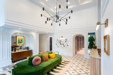 A living room with a green couch and a chandelier.