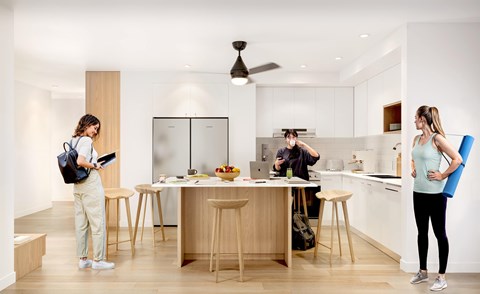 Three people are standing in a modern kitchen.