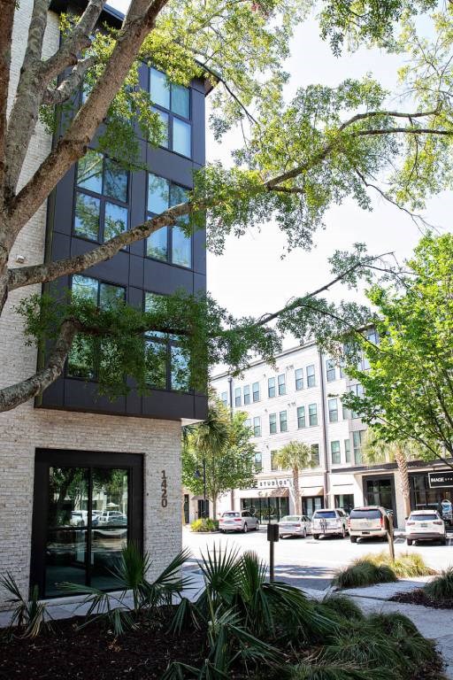 A modern building with a glass facade is surrounded by greenery.