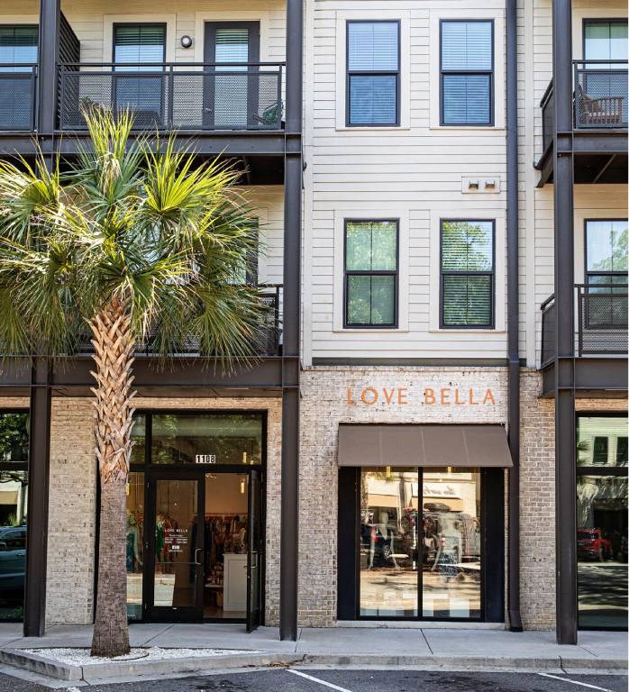 A palm tree stands in front of a building with a storefront that says "Love Bella.".