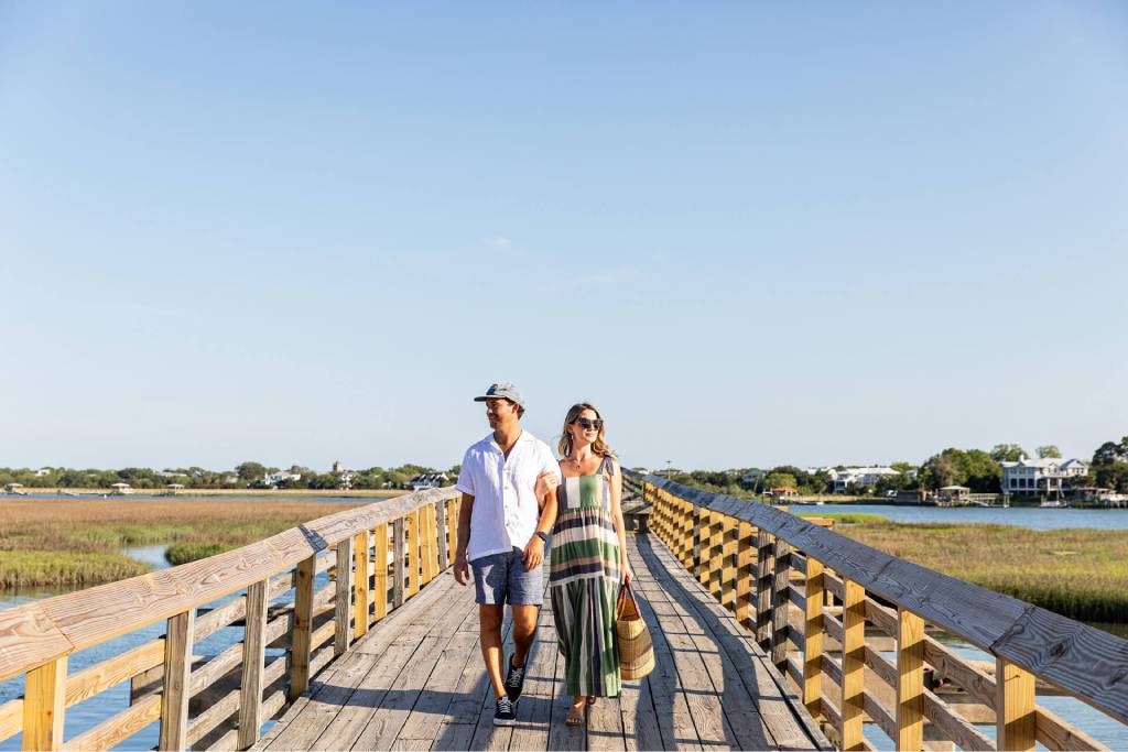 A man and a woman are walking on a wooden bridge.
